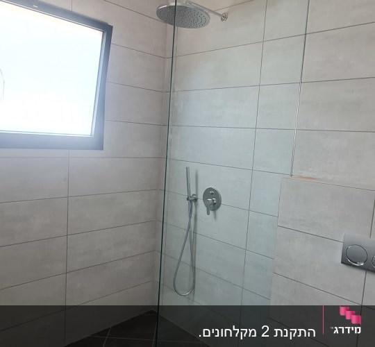 מקלחון זכוכית עם ראש מקלחת עגול וקיר אריחים